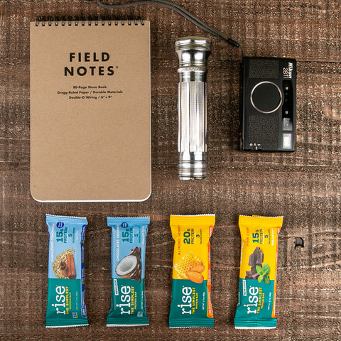 Flatlay of Rise Bars, camera, flashlight, and notepad
