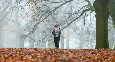 Woman running through the woods in fall