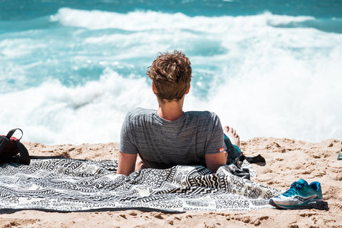 Man sitting on the beach looking out over the water
