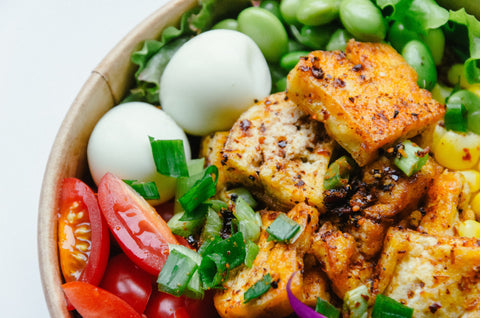 Healthy bowl with tofu, eggs, tomatoes, and edamame