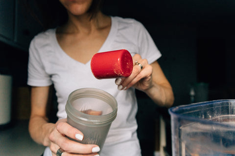 Woman adding protein to a protein shake