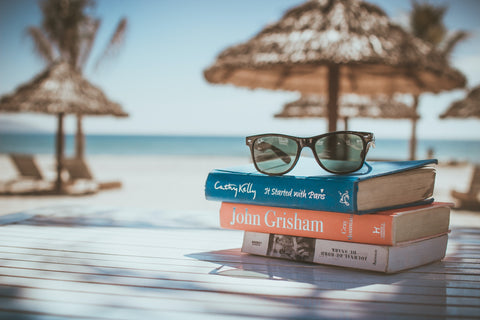 Sunglasses on top of stack of books in tropical location