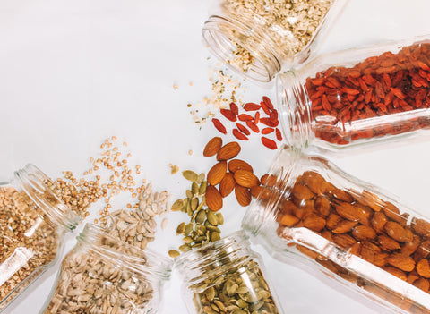 Oats, nuts, and dried fruit spilling out of jars
