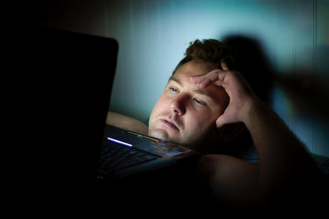 Man laying in bed looking at laptop screen